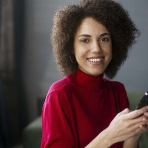 african american woman in red casual attire using mobile phone working online text messaging